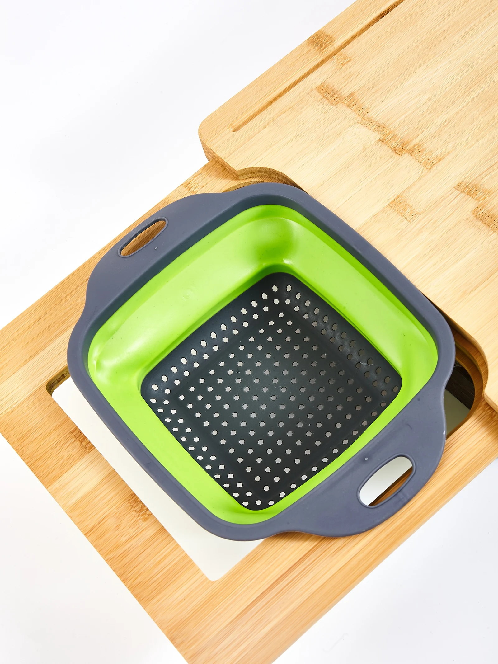 Bamboo cutting board with collapsible colander seated in the prep cutout