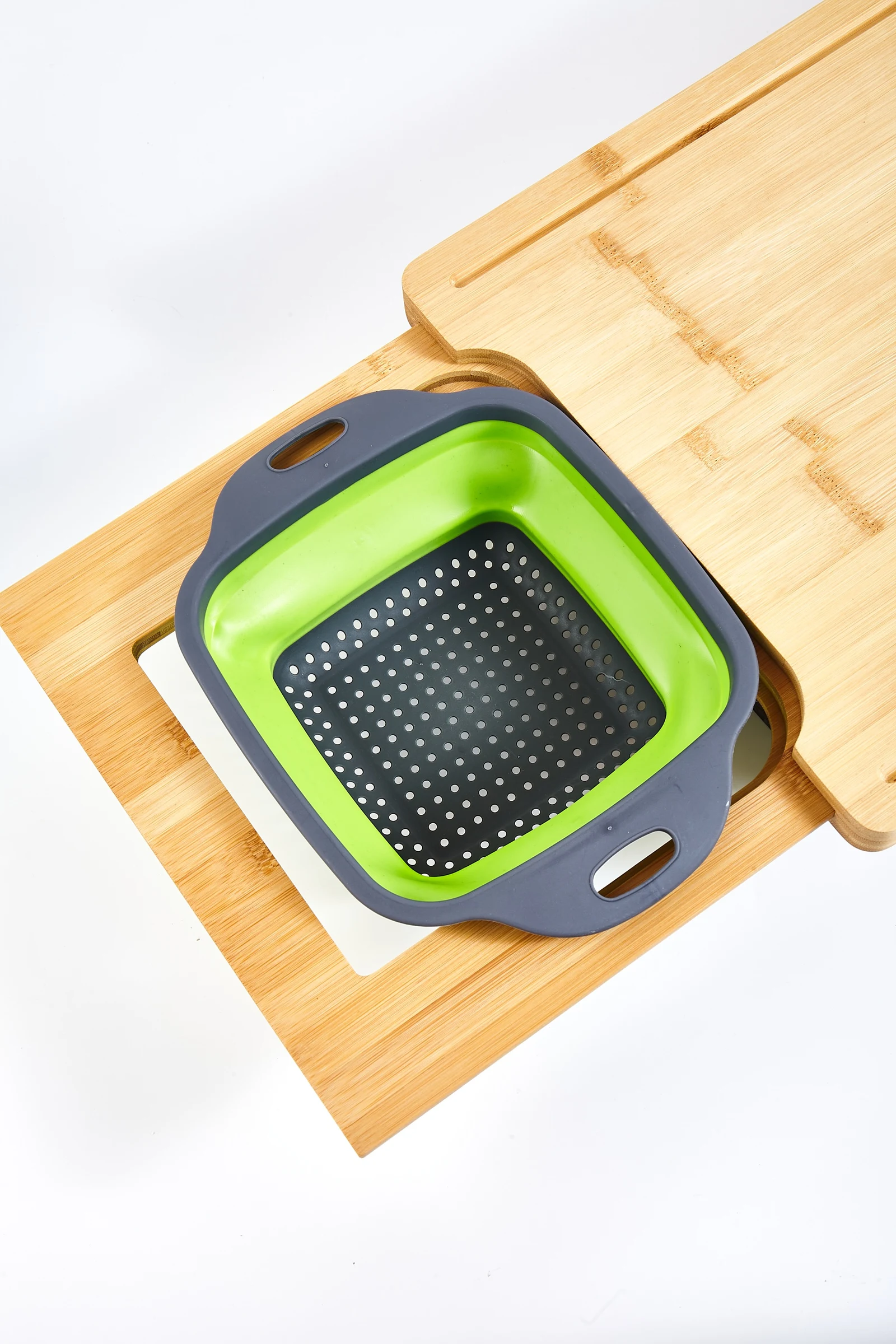Collapsible colander nested in the bamboo cutting board cutout